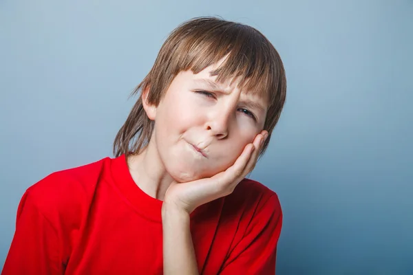 Ragazzo dall'aspetto europeo di dieci anni mal di denti, mano sulla guancia su un — Foto Stock