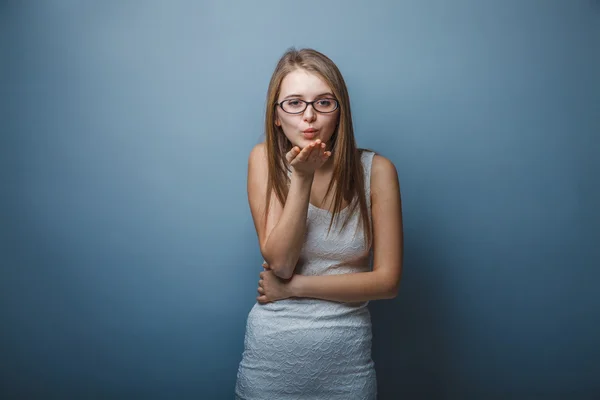 Європейський дивлячись дівчинка в окулярах двадцять років, передає поцілунок за — стокове фото