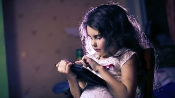 Девочка-подросток, играющая в комнате в вечерней планшетной брюнетке шесть лет — стоковое видео