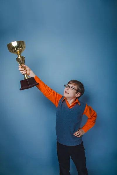 Ragazzo dall'aspetto europeo di dieci anni premiazione coppa gioia su uno schienale grigio — Foto Stock