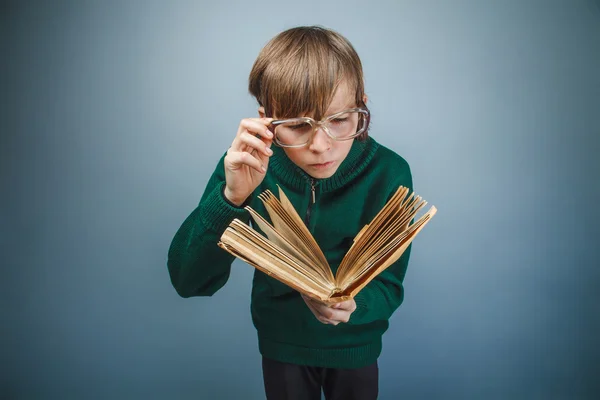 Europeiska-ser pojke på tio år i glas läser en bok på — Stockfoto