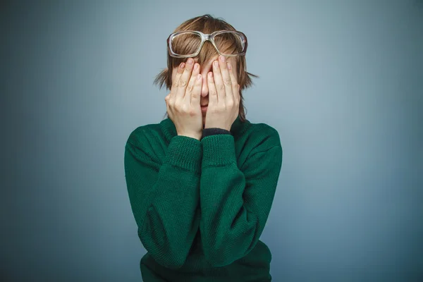 European-looking boy of ten years in glasses covered his face wi — Stock Photo, Image