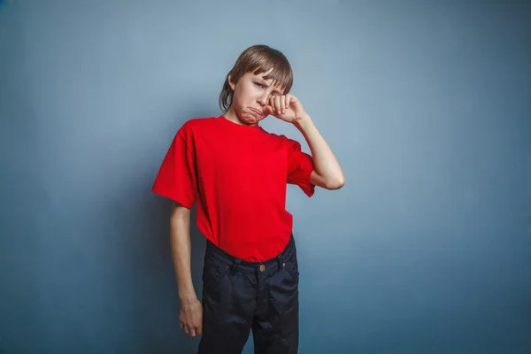 Boy, teenager, twelve years in the red T-shirt, hand wipes tears — Stock Photo, Image