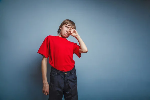 Мальчик, подросток, 12 лет в красной футболке, руки вытирают слезы, с — стоковое фото