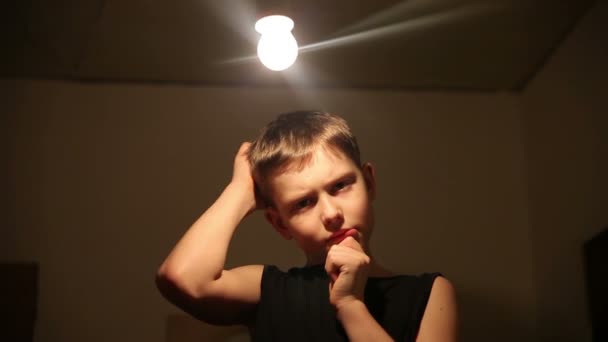 Tinédzser fiú tíz évvel azt hiszi izzó a fejére a eszme-ból egy sötét háttér videóinak 1920 x 1080 hd — Stock videók