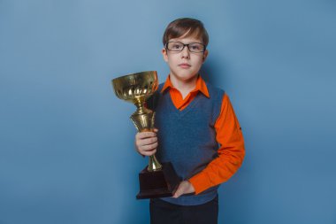 Avrupa görünümlü çocuk on yıllık bir fincan, Ödülü sevinç mavi bir arka plan üzerinde tutarak gözlük