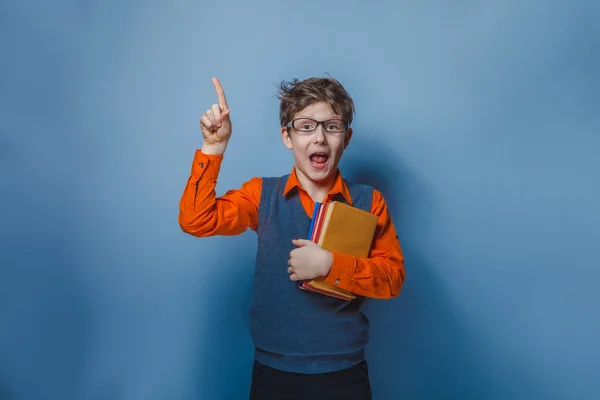 Niño de aspecto europeo de diez años en gafas pulgares hacia arriba, la idea del libro sobre un fondo gris —  Fotos de Stock