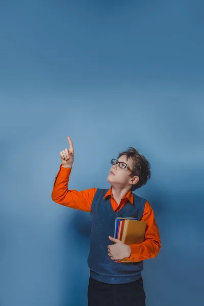 Niño de aspecto europeo de diez años en gafas pulgares hacia arriba, la idea del libro sobre un fondo azul —  Fotos de Stock