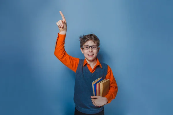 Niño de aspecto europeo de diez años en gafas pulgares hacia arriba, la idea del libro sobre un fondo azul —  Fotos de Stock