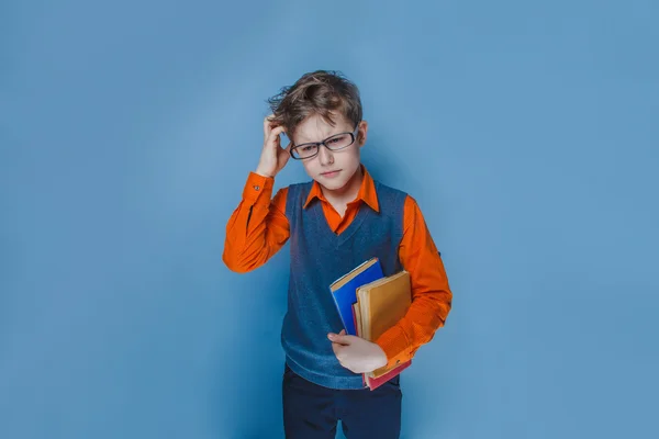 Europejskiej Szukam chłopaka dziesięć lat w okularach myślenia uważnie książki na niebieskim tle — Zdjęcie stockowe