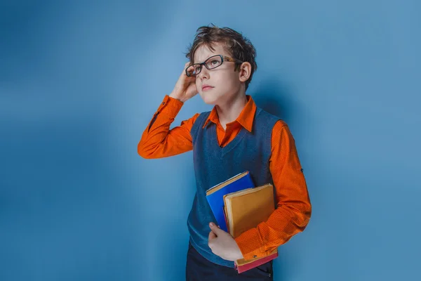 Ragazzo dall'aspetto europeo di dieci anni con gli occhiali che pensa intensamente a prenotare su uno sfondo blu — Foto Stock