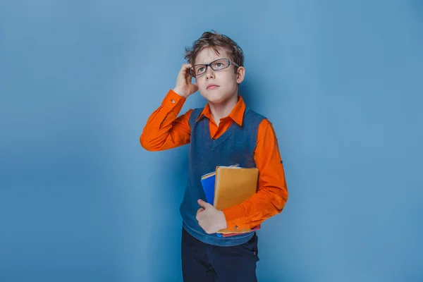 Ragazzo dall'aspetto europeo di dieci anni con gli occhiali che pensa intensamente a prenotare su uno sfondo blu — Foto Stock