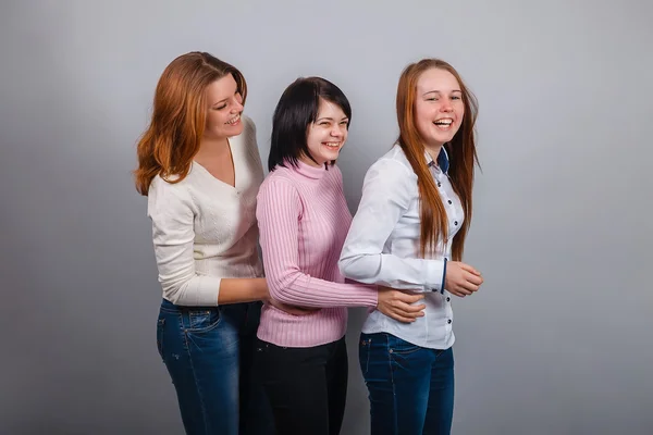 Three girls woman girlfriends hugging joy happiness friendship on a gray background studio — Stock Photo, Image