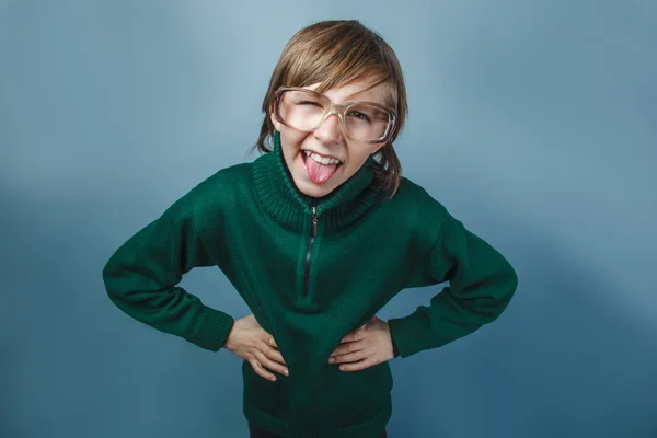 European-looking  boy of  ten years shows tongue teases on a blue background — Stock Photo, Image