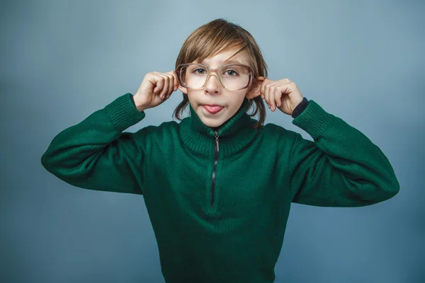 Chico de aspecto europeo de diez años muestra burlas lengua sobre un fondo azul —  Fotos de Stock