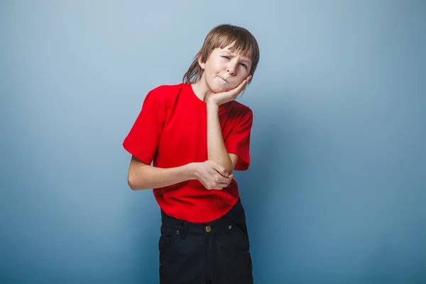 Menino adolescente europeu aparência mantém uma mão na bochecha em um — Fotografia de Stock