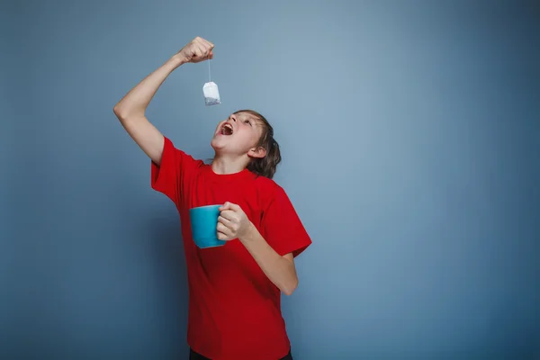 Dospívající chlapec evropských vystoupení v červené košili držící šálek — Stock fotografie
