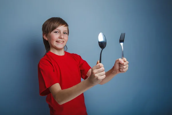 Boy teenager European appearance in a red shirt holding a fork a — Stock Photo, Image