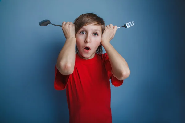 Jongen tiener Europese verschijning in een rood shirt zet vork en spo — Stockfoto