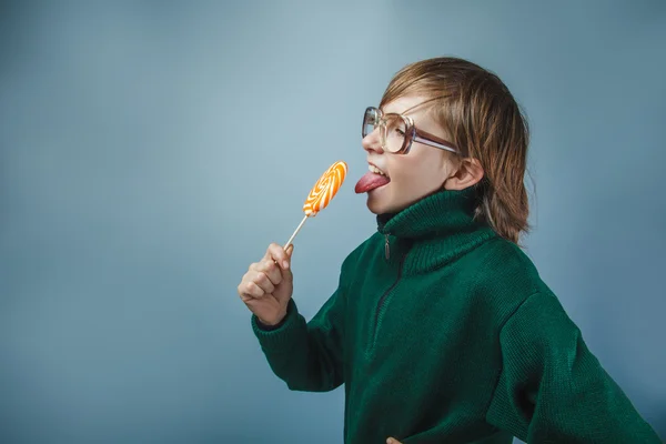 European-looking  boy of ten years in glasses licking a lollipop — Stock Photo, Image