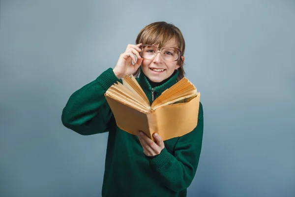 Europäisch aussehender Junge mit Brille und einem Buch in der Hand. — Stockfoto