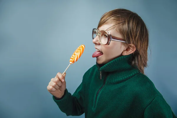 Europäisch aussehender Junge von zehn Jahren in Brille leckt einen Lutscher — Stockfoto