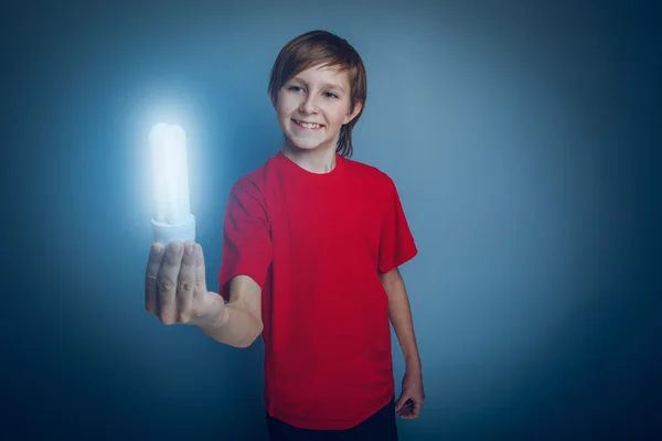 Teenage boy European appearance in a red shirt holding a burning — Stock Photo, Image