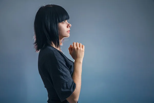 Europese uitziende meisje brunette in zwarte jas gevouwen haar handen — Stockfoto