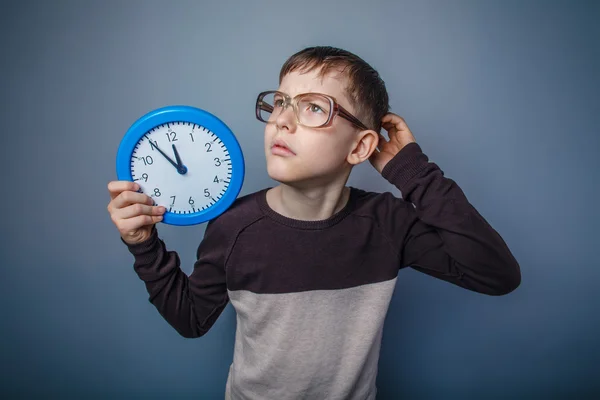 Teenager boy of European appearance with glasses holding a clock — Stock Photo, Image