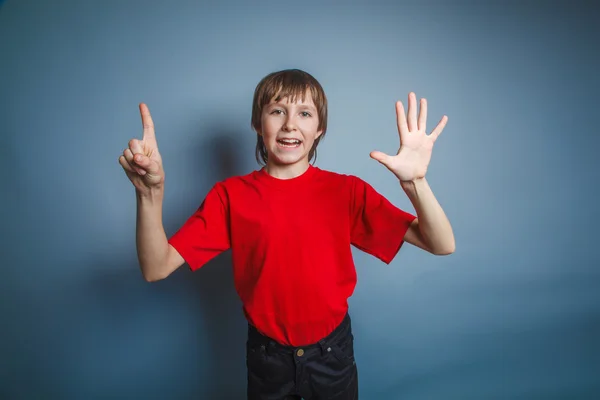 Teenager boy brown European appearance in a red shirt shows the — Stock Photo, Image