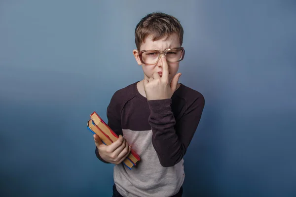 Europeiska-ser pojke på tio år i glas håller en bok i h — Stockfoto