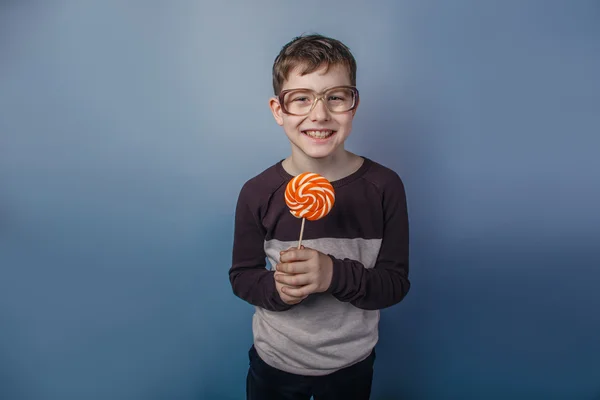 European-looking  boy of ten years in  glasses licking a lollipo — Stock Photo, Image