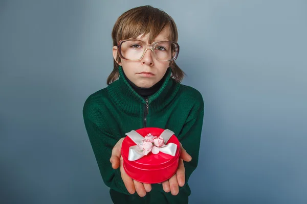 Europäisch aussehender Junge von zehn Jahren in einer Brille mit einer Geschenkbox — Stockfoto