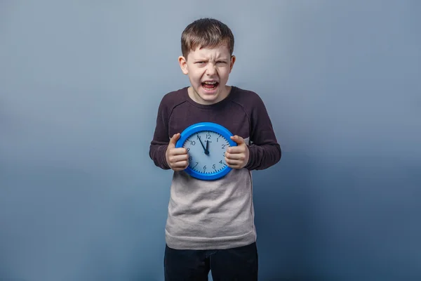 European-looking boy of ten years holding a wall clock opened hi — Stock Photo, Image