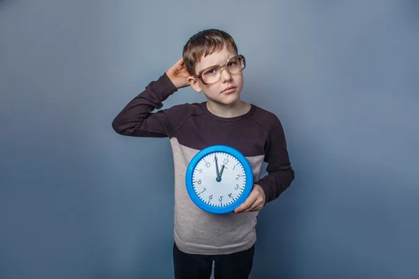 European-looking boy of ten years holding a wall clock reflected — Stock Photo, Image