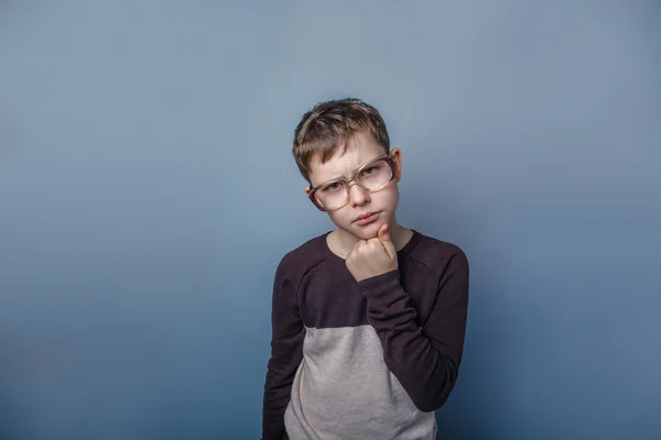 Europäisch aussehender Junge von zehn Jahren mit Brille, der auf einem grauen Kopf denkt — Stockfoto