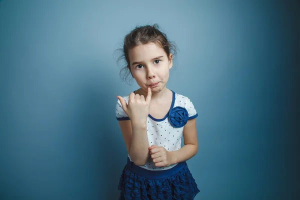 A girl of seven European appearance brunette licks a finger on a — Stock Photo, Image