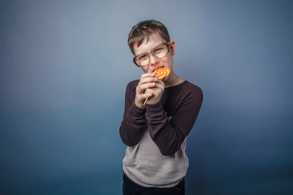 Ragazzo adolescente aspetto europeo in occhiali da sole mordicchia caramelle col — Foto Stock