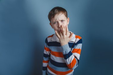 On yaşında çocuk Avrupa görünümlü gri bir bac üzerinde parmağını yalıyor