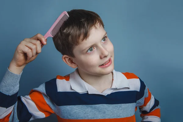 European-looking boy of ten years combing her hair on a gray bac — Stock Photo, Image