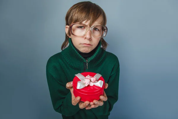 Europeiska-ser pojke på tio år i glas håller en presentförpackning — Stockfoto