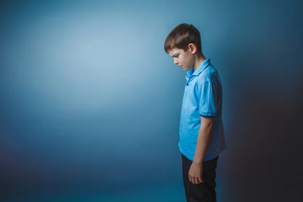 Boy teenager European appearance in a blue shirt brown hair hung — Stock Photo, Image