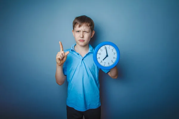 Adolescente ragazzo marrone aspetto europeo tiene un orologio che mostra gio — Foto Stock