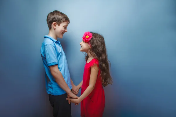 Gadis remaja berpegangan tangan remaja laki-laki di latar belakang abu-abu — Stok Foto