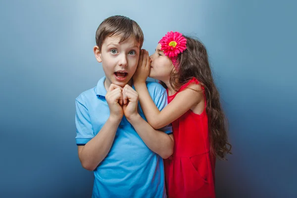 Teenage girl whispering in the ear of a secret teen boys on a  g — Stock Photo, Image