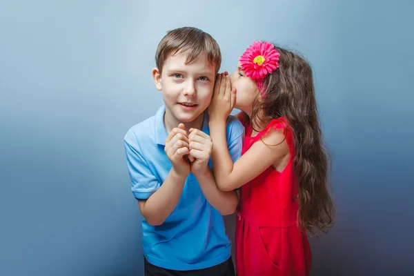 Dospívající dívka šeptá do ucha tajné dospívajících chlapců na skupi — Stock fotografie