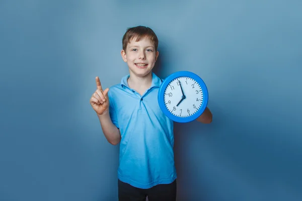 Niño adolescente europeo apariencia diez años celebración de un reloj de pared — Foto de Stock