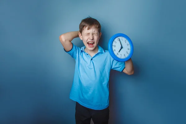 Ragazzo adolescente aspetto europeo dieci anni tenendo orologio da parete op — Foto Stock