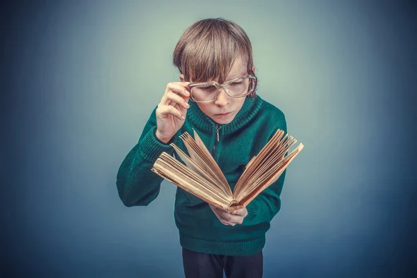 Evropská vyhlížející chlapec deseti let v brýle na čtení knihy — Stock fotografie