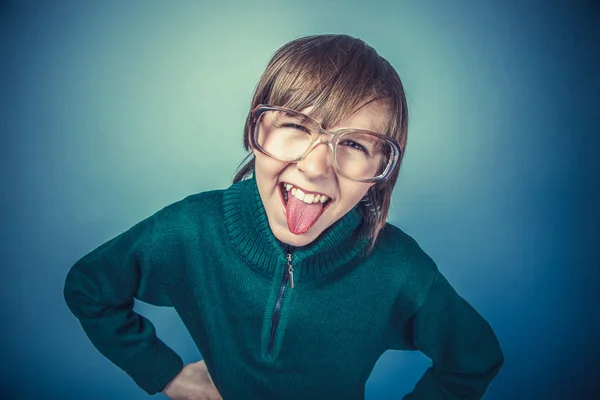 European-looking boy of ten years in glasses showing tongue on a — Stock Photo, Image